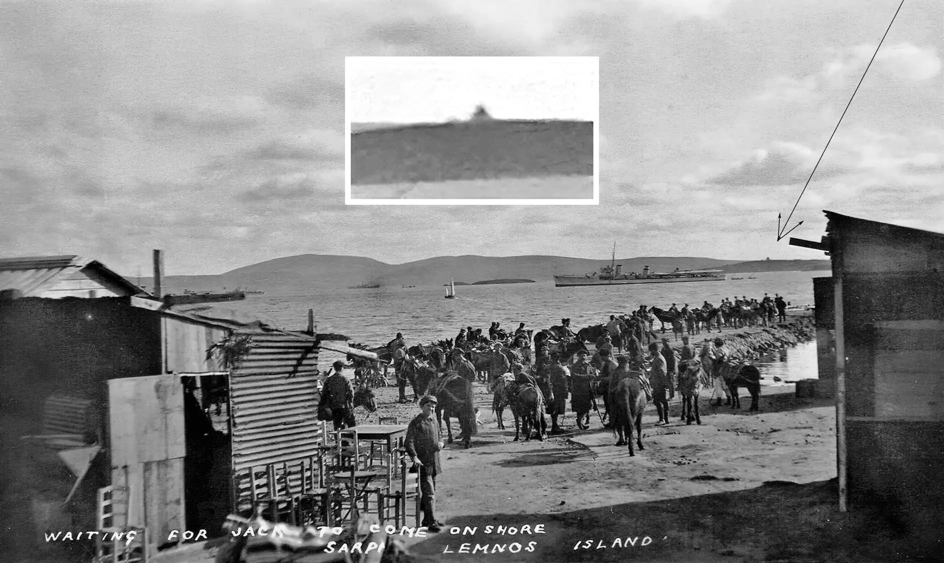 Black and white photo of a coastal scene at Lemnos Island, showing soldiers on horseback lined up along the shore. A battleship is visible on the water. A small pyramid-like structure is highlighted on a distant point.